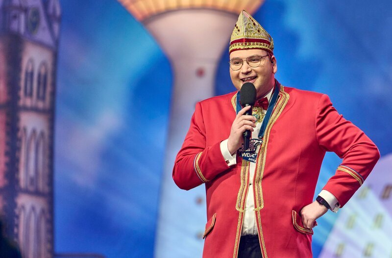 Durch die Festsitzung führt Moderator Dennis Vobis, der Präsident des Düsseldorfer Narrencollegiums. Seit mehr als 10 Jahren kennt man ihn als Co-Moderator des Bühnenprogramms zu Hoppeditz Erwachen vor dem Rathaus. – Bild: WDR/​Claus Langer