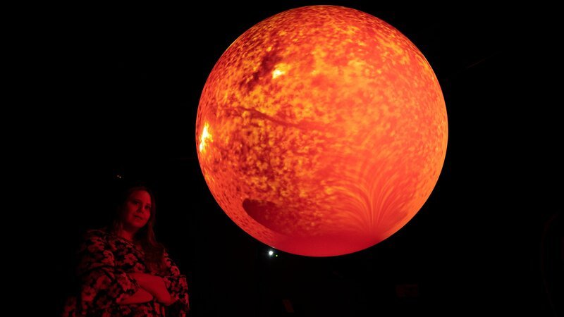 NASA-Forscherin Lisa Upton vor einem Modell der Sonne. – Bild: BBC/​Andrew Fleming