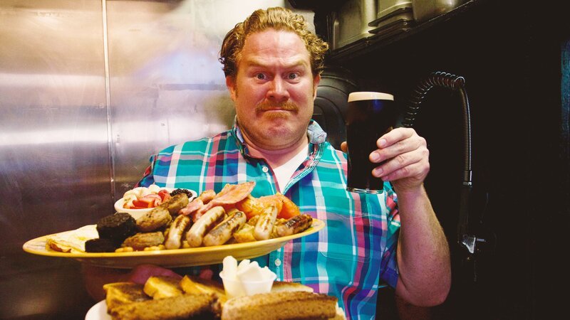 Host Casey Webb poses with the Flann O’Brien’s Guinness Breakfast Challenge, as seen on Man v. Food. – Bild: Cooking Channel – US. /​ Focus.