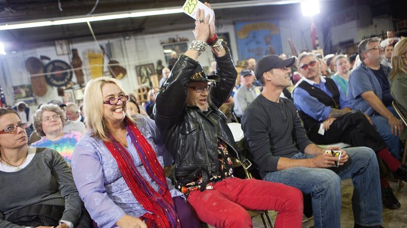 Laurence holds up his number and celebrates a winning bid in Nashville as Sally sits nearby and smiles. – Bild: The Travel Channel, L.L.C.