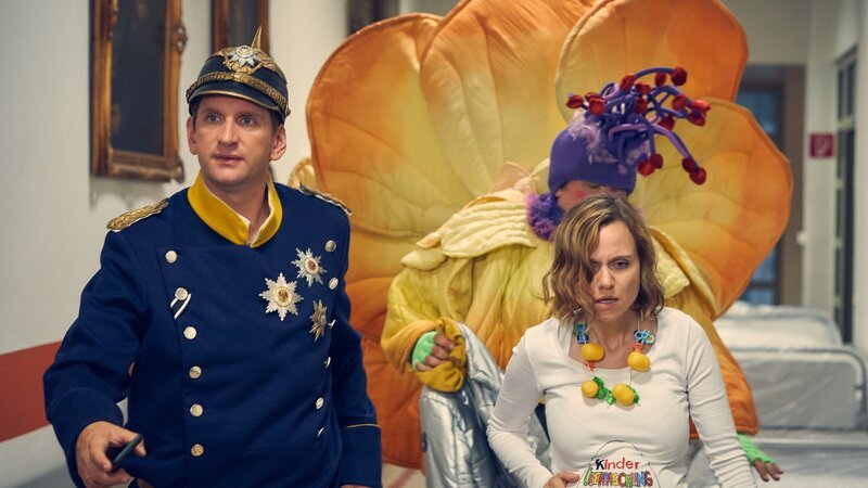 Lars (Sebastian Schwarz, l.) und Malte (Daniel Zillmann, 2.v.r.) begleiten Anita (Nadja Becker, r.), deren Wehen mitten im Karneval eingesetzt haben, ins Krankenhaus. – Bild: ZDF und Frank Dicks