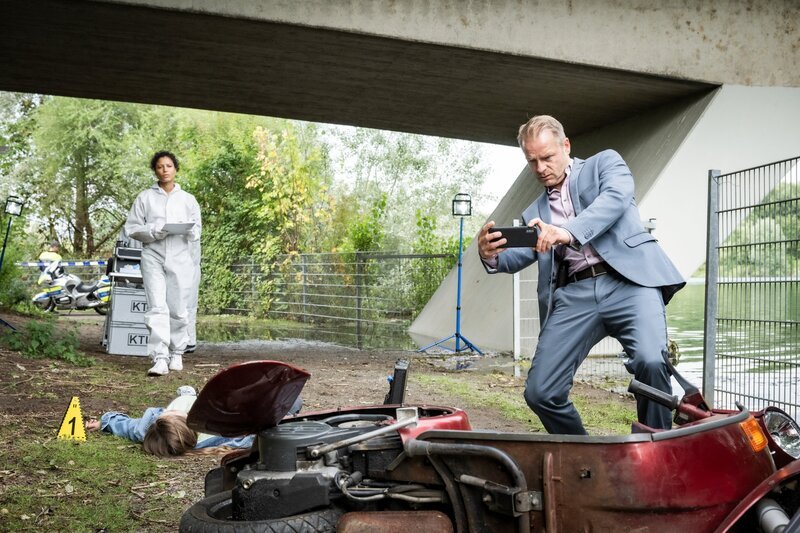 Gerichtsmedizinerin Dr. Magda Zimmer (Davina Donaldson, l.) bietet Jürgen Simmel (Hinnerk Schönemann, r.) an, einen Bluttest des Opfers Alice Taylor (Sonja Joanne Geller) für spezielle Hinweise zu machen. – Bild: ORF/​ZDF/​Martin Valentin Menke