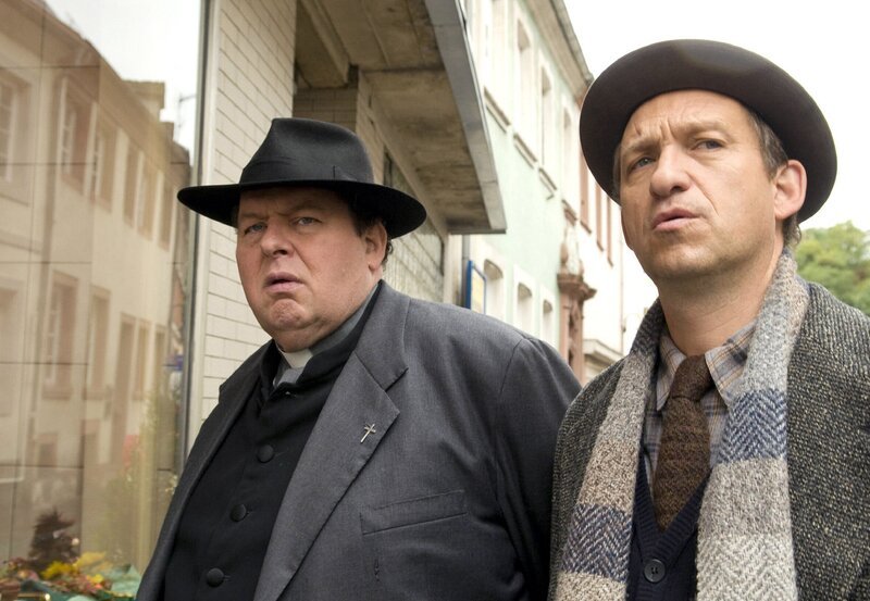 Kommissar Geiger (Peter Heinrich Brix, re.) verhaftet Pfarrer Braun (Ottfried Fischer). – Bild: ARD Degeto/​Manuela Meier