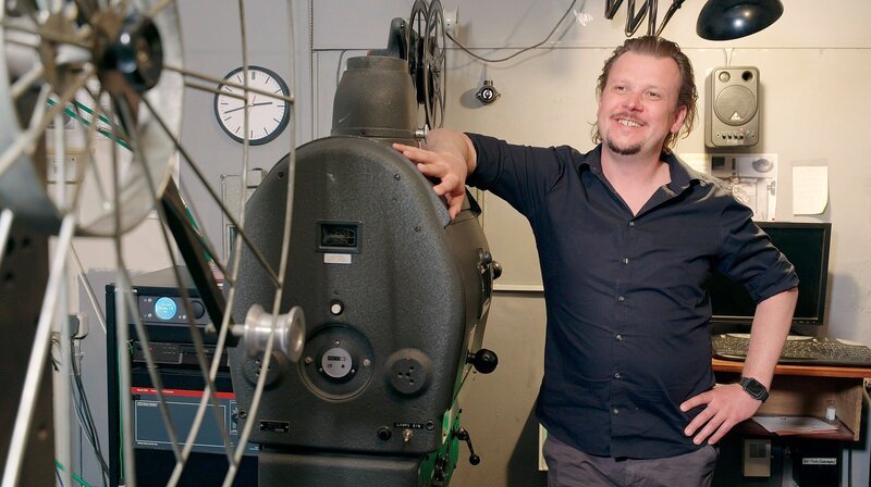 André Jansen, Betreiber des Berli Theater in Hürth-Berrenrath, an einem alten Filmprojektor. – Bild: WDR/​Broadview TV/​Alexandra Brandt