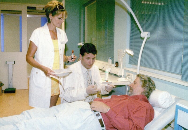 Roland Heilmann (Thomas Rühmann), assistiert von Schwester Yvonne (Maren Gilzer), untersucht Costa (Martin Huber). – Bild: MDR