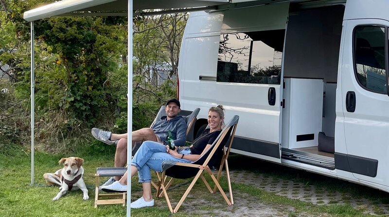 Svenja (r) und Jan Krüger vor ihrem Glamping Van auf einem Campingplatz in den Dünen von Nordholland. – Bild: WDR/​sagamedia