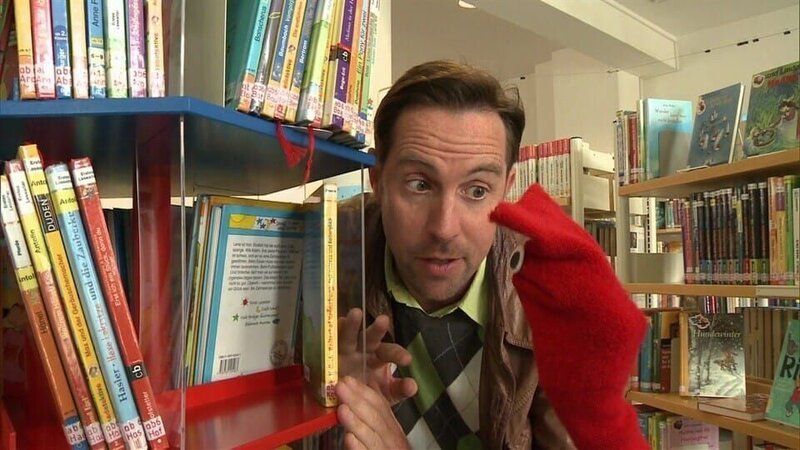 David und Red besuchen eine Bücherei. – Bild: Kinderkanal