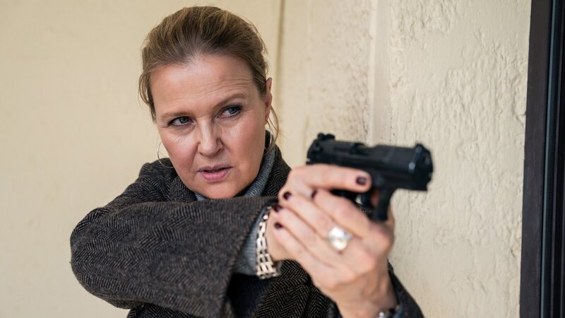 Die Polizeikommissarin steht vor einer Hauswand mit gezogener Waffe: Katharina Böhm als Vera Lanz – Bild: SRF/​ZDF/​Marc Reimann