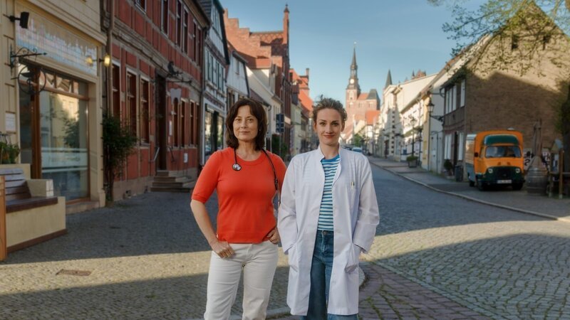 Die Spurensuche nach ihrer leiblichen Mutter führt Dr. Holly Sass (Karoline Teska, r.) in die Praxis von Dr. Katrin Herz (Inka Friedrich, l.). Da diese gerade eine Vertretung sucht, findet sich Holly unversehens als Landärztin wieder. – Bild: ZDF und Stefan Erhard