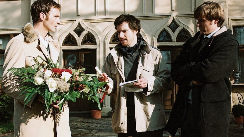 Ein Blumenbote (Komparse, M.) versucht vergeblich, Bianca ausfindig zu machen. Oliver (Patrik Fichte, l.) und Eddie (Christoph Mory, r.) können auch nicht weiterhelfen. – Bild: ZDF und Britta Krehl