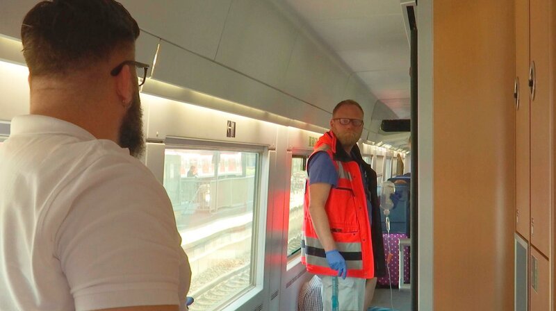 Notarzt Sven Jansen (rechts) und Notfallsanitäter Marcus Müller betreuen im ICE eine bewusstlose Patientin. – Bild: HR/​Pressestelle