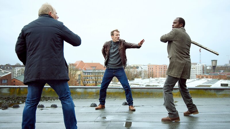Jon (Alois Moyo, r.) ist außer sich – Falke (Wotan Wilke Möhring, M.) versucht, das Schlimmste zu verhindern (mit Michael Lott, v.) – Bild: NDR/​O-Young Kwon