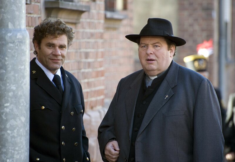 Pfarrer Braun (Ottfried Fischer, rechts) stellt Jean-Luc Schwaderlapp (Wolfgang Maria Bauer) einige Fragen. – Bild: Manuela Meier