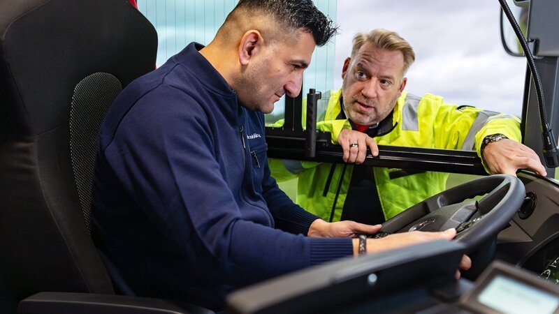 Fahrlehrer Bastian Peters (r.) bringt dem Quereinsteiger Kemal Isci (l.) das Busfahren bei. In rund vier Monaten macht er eine Ausbildung zum Busfahrer. – Bild: ZDF und Benjamin Wistorf