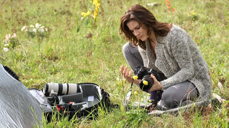Franziska Loer versucht trotz ihrer schmerzenden Hand, für einen Fotokalender Blumen zu fotografieren. – Bild: ARD Degeto/​Hardy Spitz