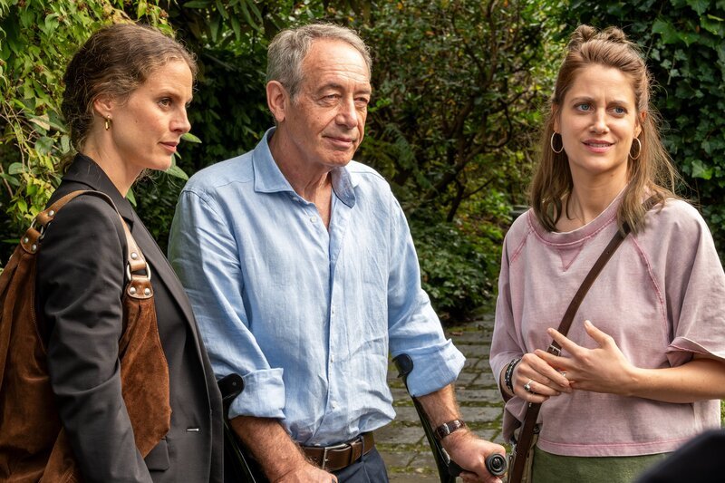 Dass sich Wolfgangs (Robert Hunger-Bühler, M.) neue Ferienbekanntschaft um ihn kümmern will, erstaunt die beiden Töchter Jana (Picco von Groote, l.) und Verena (Bettina Burchard, r.). Während Jana noch misstrauisch ist, hegt Verena keine Zweifel an Karolas ernsthaftem Interesse an Wolfang. – Bild: susanne bernhard /​ ZDF und susanne bernhard