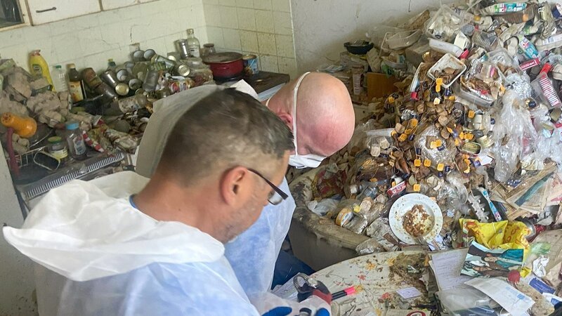 Ralf Gerstenlauer stands with his employee Jürgen Heck in a hoarder’s apartment – Behind The Scenes – Bild: Warner Bros. Discovery, Inc. or its subsidiaries and affiliates