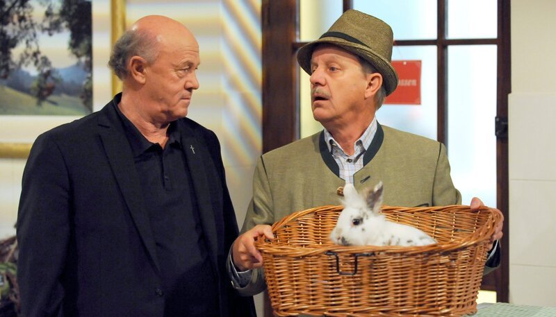 Schattenhofer ist von der Idee, als Streitschlichter beim Kaninchenstreit zu agieren, nicht so begeistert. Von links: Pfarrer Kurz (Hans Stadlbauer) und Bürgermeister Schattenhofer (Werner Rom). – Bild: BR/​Marco Orlando Pichler
