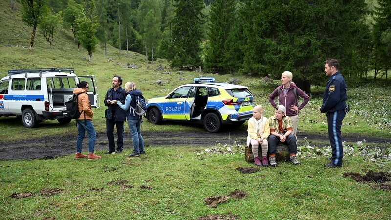 Siggi Loisl (Sebastian Gerold, r.) wartet mit Elise Lechner (Alexandra von Schwerin, 2.v.r.), Paul (Maximilian Kaiser, 3.v.r.) und Hailey (Hanna Heckt, M.) auf den Rettungswagen, während Charly (Thomas Birnstiel, 2.v.l.) potentielle weitere Zeuginnen des Unfalls befragt. – Bild: Barbara Bauriedl /​ ZDF
