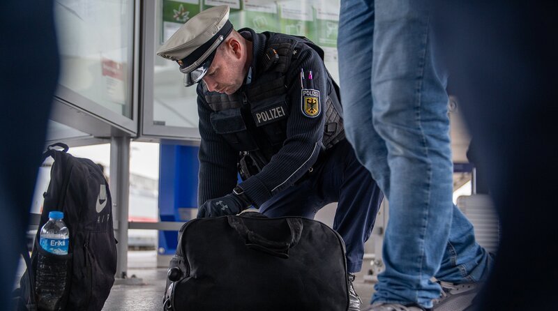 Bundespolizist Dennis Hehemann durchsucht die Tasche eines Verdächtigen. – Bild: NDR/​ Noah Siegert