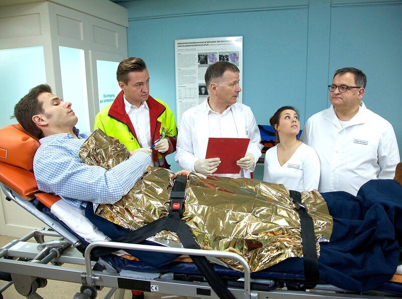 Medizinstudent Mirko Wollert ist im Badezimmer gestürzt und wird in die Sachsenklinik eingeliefert. Der Notarzt vermutet ein stumpfes Bauchtrauma. Pfleger Hans-Peter Brenner erkennt Mirko sofort als seinen Kommilitonen. – Bild: MDR/​Saxonia/​Wernicke