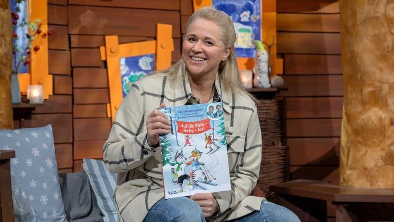 Singa hat einen Buchtipp mitgebracht. Sie stellt das Buch „Auf die Piste – fertig – los!“ vor. – Bild: KiKA