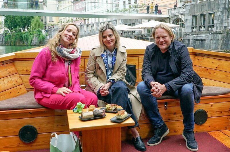Tamina Kallert (l), Björn Freitag und Gastgeberin Valentina (M) erkunden Ljubljana vom Wasser aus, inklusive Struklji-Verkostung an Bord. – Bild: WDR/​2bild GmbH