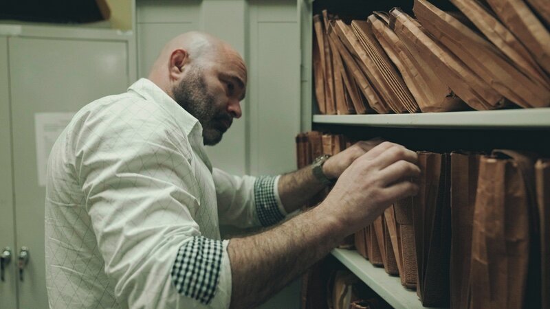 Ein Mann durchsucht Polizeiakten auf einem Regal im Archivraum. – Bild: Crime + Investigation /​ A+E Global Media