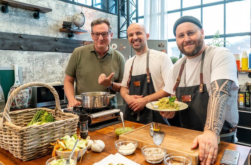 Themen der Sendung: Beipackzettel and Brownbag, Restekochen mit Familie Brajdic, Long Covid. V.l.n.r. Eckart von Hirschhausen mit Toni Brajdic und dem Koch Philipp Zitterbart – Bild: ARD/​Max Kohr