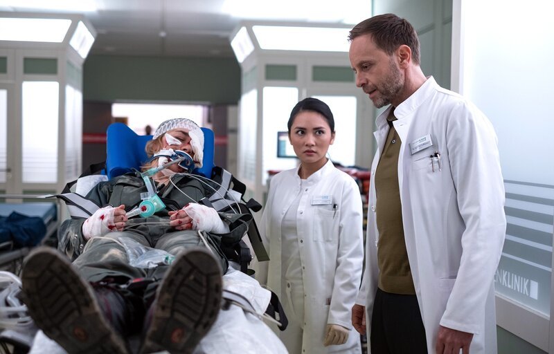 Nika Freese (Henrike Hahn, li.) wird nach einer Explosion bei einer Bombenentschärfung mit schwersten Verwundungen eingeliefert. Dr. Lilly Phan (Mai Duong Kieu, mi.) bittet Dr. Kai Hoffmann (Julian Weigend, re.) um Unterstützung. Er hat die meisten Erfahrungen. – Bild: MDR/​Saxonia Media/​Robert Strehler