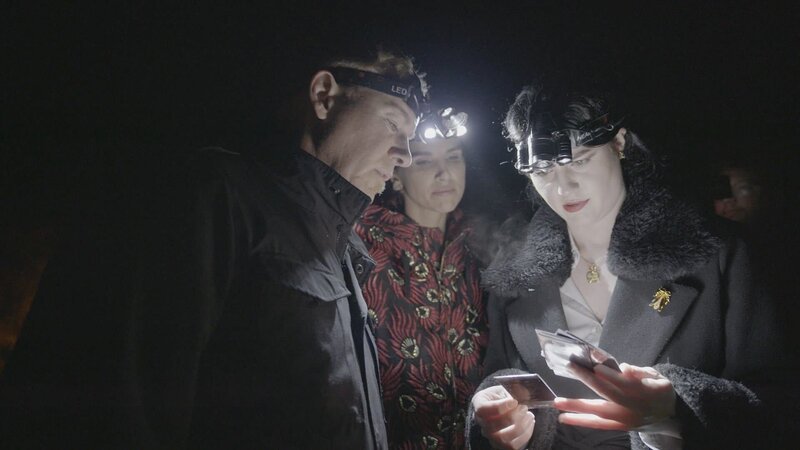 Evelyn reviews photographs at the final vigil – Bild: Really /​ Discover Images: RXDW103_28 /​ © 2023 Warner Bros. Discovery, Inc. or its subsidiaries and affiliates. All rights reserved.