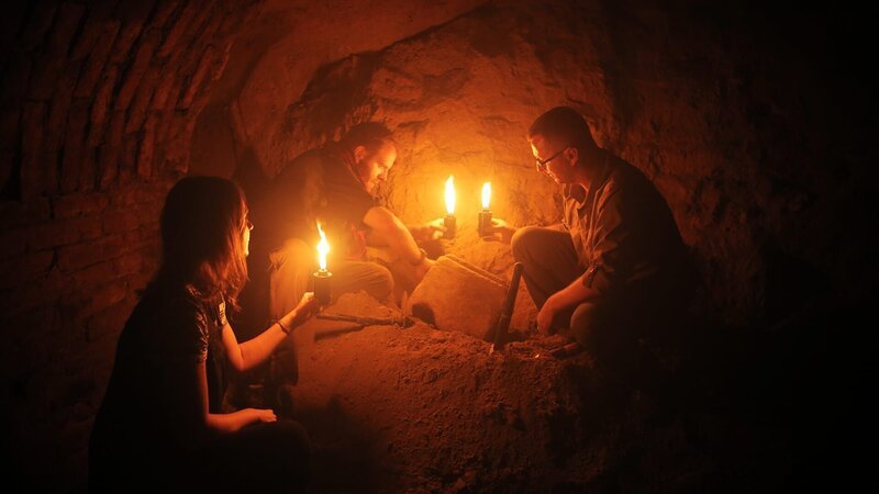 Josh Gates, Dr. Norbert Pap, and Erika Hancz search the dark recesses of a wine cellar. – Bild: Warner Bros. Discovery