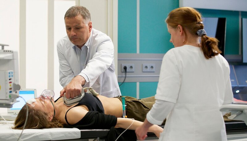 MDR Fernsehen IN ALLER FREUNDSCHAFT FOLGE 658, „Herzstillstand“, am Mittwoch (29.10.14) um 11:45 Uhr. Für Dr. Roland Heilmann (Thomas Rühmann) ist es ziemlich unwahrscheinlich, dass psychische Probleme die Ursache für Kerstin Hellers (Rike Schäffer, li.) Ohnmachtsanfälle sind. Als sie dann wie aus dem Nichts schwere Herzrhythmusstörungen bekommt, haben er und die Schwester (Komparsin, re.) Probleme, sie wieder zu stabilisieren. – Bild: MDR/​Wernicke