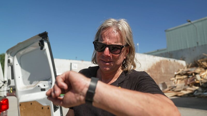 Jörg Hartmann stands with sunglasses in the yard of the recycling company, looks at the clock – Bild: DMAX