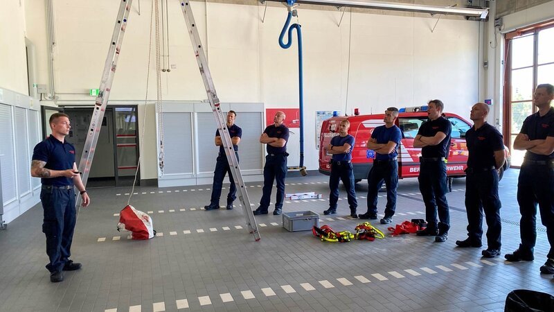 Die Männer am Bahnhof trainieren den Umgang mit einem Abseilgerät, das auch für die Rettung aus Höhen eingesetzt wird. – Bild: Warner Bros. Discovery, Inc. or its subsidiaries and affiliates.