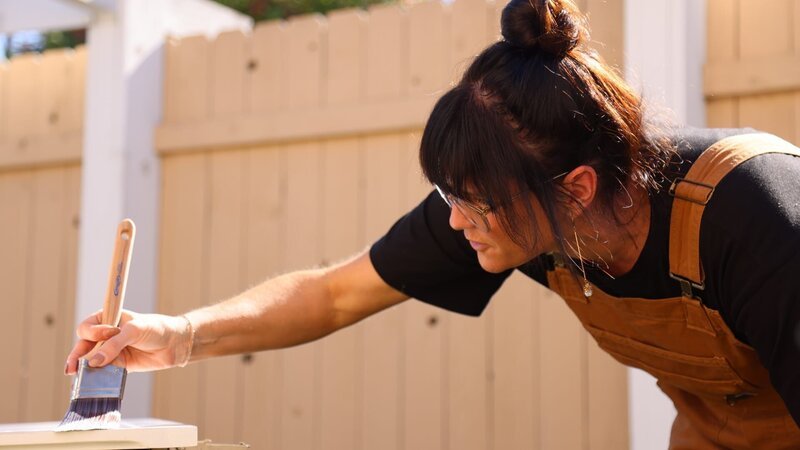 Lyndsay paints a door for the Peters family’s home – Bild: Warner Bros. Discovery, Inc.