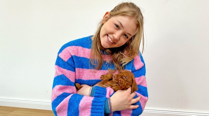 Der kleine Magyar Vizsla auf Ninas Arm wird, wenn er mal groß ist, immer noch sehr verschmust sein, aber auch sehr viel Beschäftigung brauchen. – Bild: BR/​Text und Bild Medienproduktion GmbH & Co. KG/​Katharina Brackmann