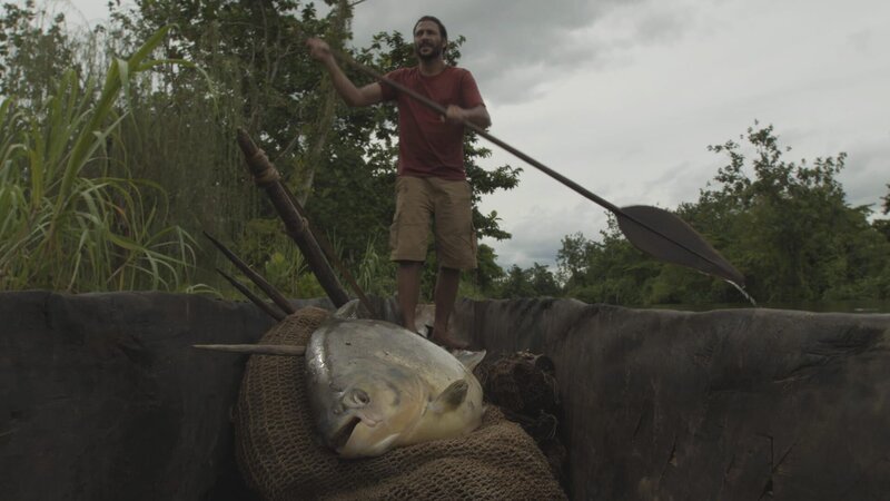 PAPUA NEW GUINEA – Hazen paddling with a large paku he caught, which will be presented as a gift to the villagers he is heading towards. – Bild: The National Geographic Channel