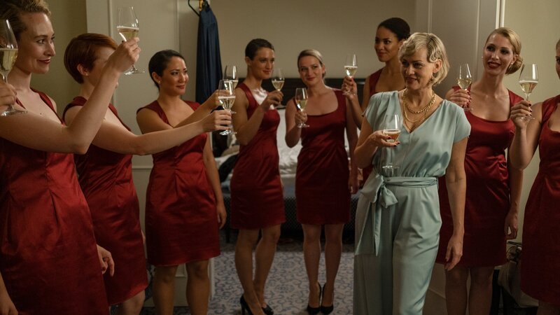 Agenturchefin Ines Bezold (Gesine Cukrowski, 3.v.r.) schwört ihre Hostessen ein, an diesem Abend gute Laune zu verbreiten, darunter Kim Krawitz ( Friederike Becht, 5.v.l.) und Maja Heller (Nina Gummich, M.). – Bild: Christine Schroeder /​ ZDF