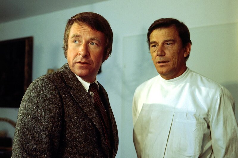 Dr. Kerrut mag zwar als Arzt für die Polizei ohne Interesse sein, aber in seinem Privatleben gibt es einige Punkte, die Grabert unbedingt aufklären möchte. (V.li.: Günther Schramm, Helmut Lange). – Bild: ZDF /​ Neue Münchner Fernsehproduktion