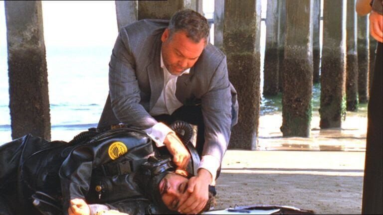 Am Strand von Coney Island wird die Leiche eines jungen Mannes (Amir Arison, liegend) im Taucheranzug angeschwemmt. Detective Robert Goren (Vincent D’Onofrio) entdeckt, dass der Tote zwei Stichwunden aufweist und der Sauerstoffschlauch durchschnitten wurde. – Bild: VOX