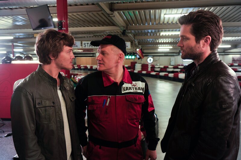 Jo Stoll (Peter Ketnath, r.) fragt sich, ob das Verhältnis des Cheftechnikers der Kartbahn, Holger Knopp (Joachim P. Assböck, M.), zu seinem Sohn Josh (Alexander Becht) wirklich so ungetrübt ist, wie die beiden Glauben machen wollen. – Bild: ZDF/​Bavaria Fernsehproduktion/​Markus Fenchel