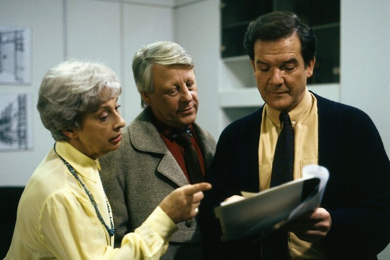 Bernhard Tenstaag (Gerhard Friedrich, r.) klagt über zu viele Überstunden. Doch Werkmeister Eberhard (Stefan Oralc) ist wieder einmal anderer Meinung als sein Chef. Neueinstellungen sind nötig, meint er. Die Sekretärin Fräulein Glaubrecht (Gudrun Genest) ist ganz auf Eberhards Seite. – Bild: ZDF und Barbara Oloffs/​Terranova