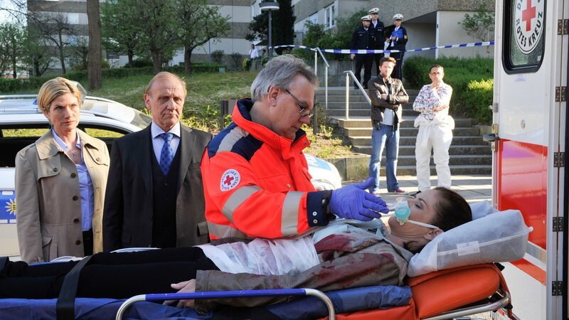 Äußerst besorgt stehen Martina Seiffert (Astrid M. Fünderich, l.) und Michael Kaiser (Karl Kranzkowski, 2.v.l.) am Krankenwagen. Selma Kirsch (Yve Burbach, liegend) ist bei einem Einsatz lebensgefährlich verletzt worden. Auch Jo Stoll (Peter Ketnath, 2.v.r.) und Jan Arnaud (Mike Zaka Sommerfeldt, r.) hoffen, dass Selma überleben wird. – Bild: ZDF und Markus Fenchel