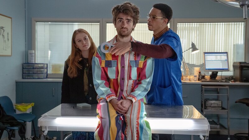 Als Jen (Máiréad Tyers, l.) und Jizzlord (Luke Rollason, M.) den Tierarzt (John Macmillan, r.) aufsuchen, macht dieser bei der Untersuchung eine Entdeckung, die Hinweise auf Jizzlords geheimnisvolles früheres Leben geben könnte. – Bild: ZDF und Laura Radford
