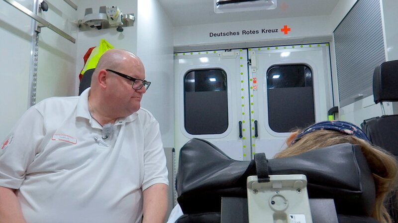 Holger Zarberg, Notfallsanitäter im Rettungswagen des Deutschen Roten Kreuzes in Kassel, versorgt eine Patientin. – Bild: HR