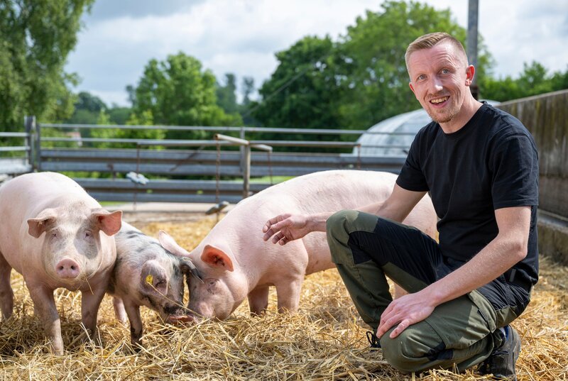 WDR Fernsehen LAND UND LECKER – WER KOCHT DAS BESTE LANDMENÜ?, „Folge 1: Borstenvieh und Hühnermodels“, am Montag (25.08.25) um 20:15 Uhr. In der ersten „Land & lecker“-Reise geht es ganz tief in den Osten von NRW, ins Dorf Pömbsen. Hier steht der Hof von Michael Peine. 2010 hat er ihn von seinen Eltern übernommen und mit neuen Ideen für frischen Schwung gesorgt. Neben der Schweinezucht gehören heute 200 Hühner zum Hof. – Bild: WDR/​Melanie Grande