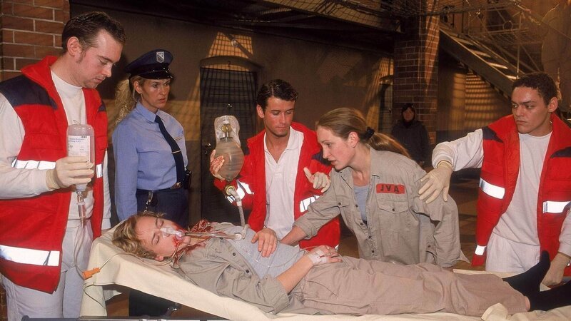 Als Fisch (Aline Staskowiak, lieg.) von den Rettungskräften (Komparsen) verletzt abtransportiert wird, flippt Kalle (Isabelle Höpfner, 2.v.re.) aus … – Bild: MG RTL D /​ Kathrin Knoke