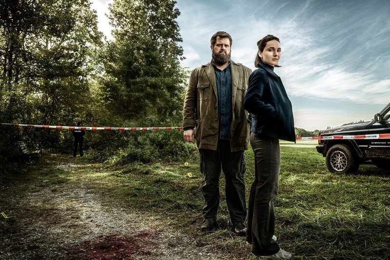 Das Keyart zu „Behringer und die Toten“ mit Behringer (Antoine Monot) und Ela (Cosima Henman). – Bild: RTL/​ Redseven Entertainment/​ Florian Froschmayer