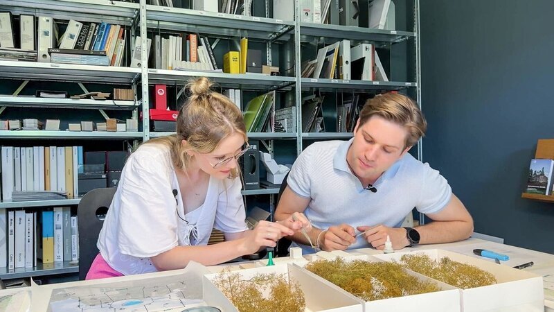 Architekt Andreas und Lena kleben Bäume auf ein Modell. – Bild: ORF